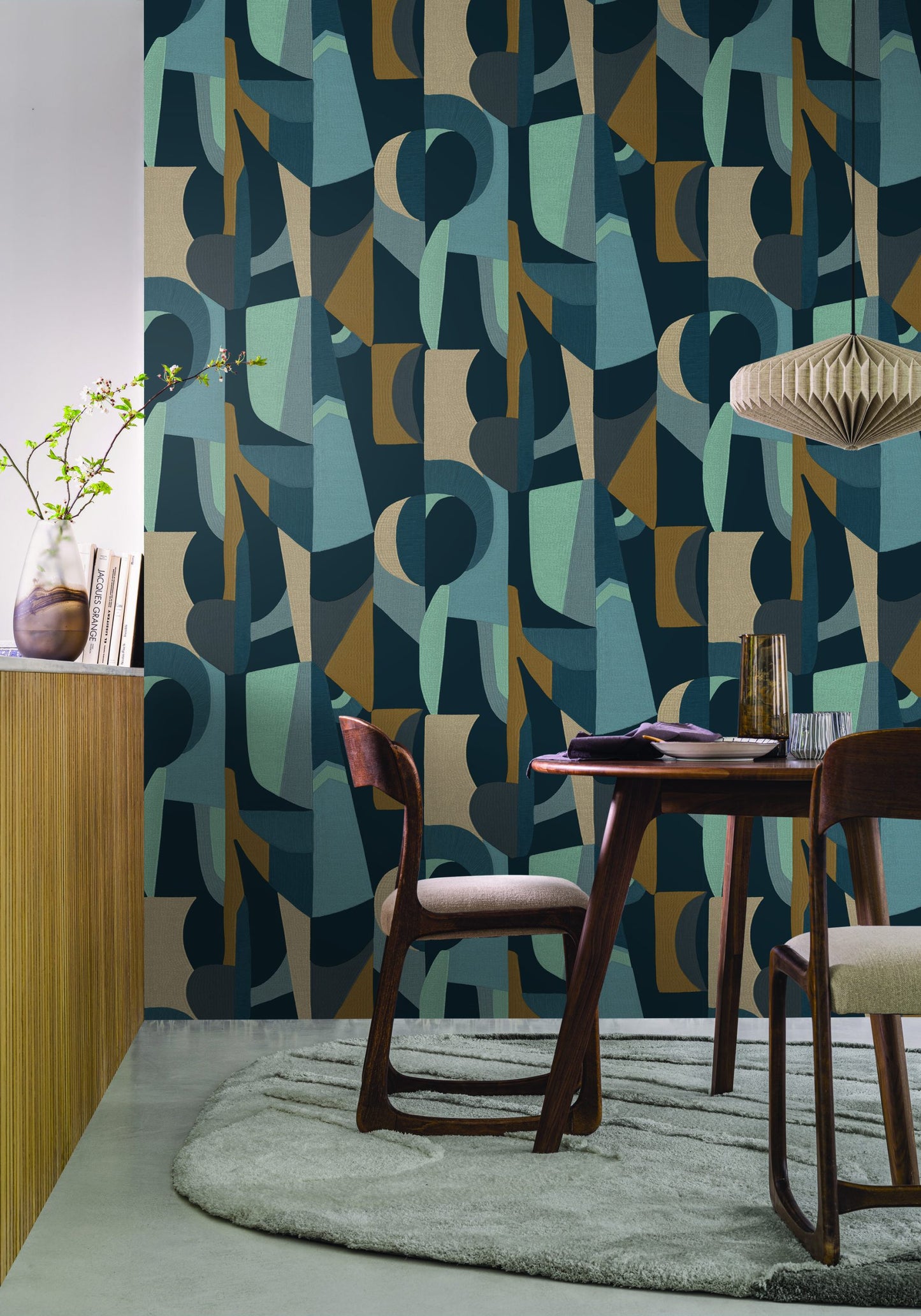 Casamance behang L'Atelier ASSEMBLAGE in de eetkamer met bruine houten tafel en stoelen met gele accesoires op tafel een groene lamp en een groen tapijt 