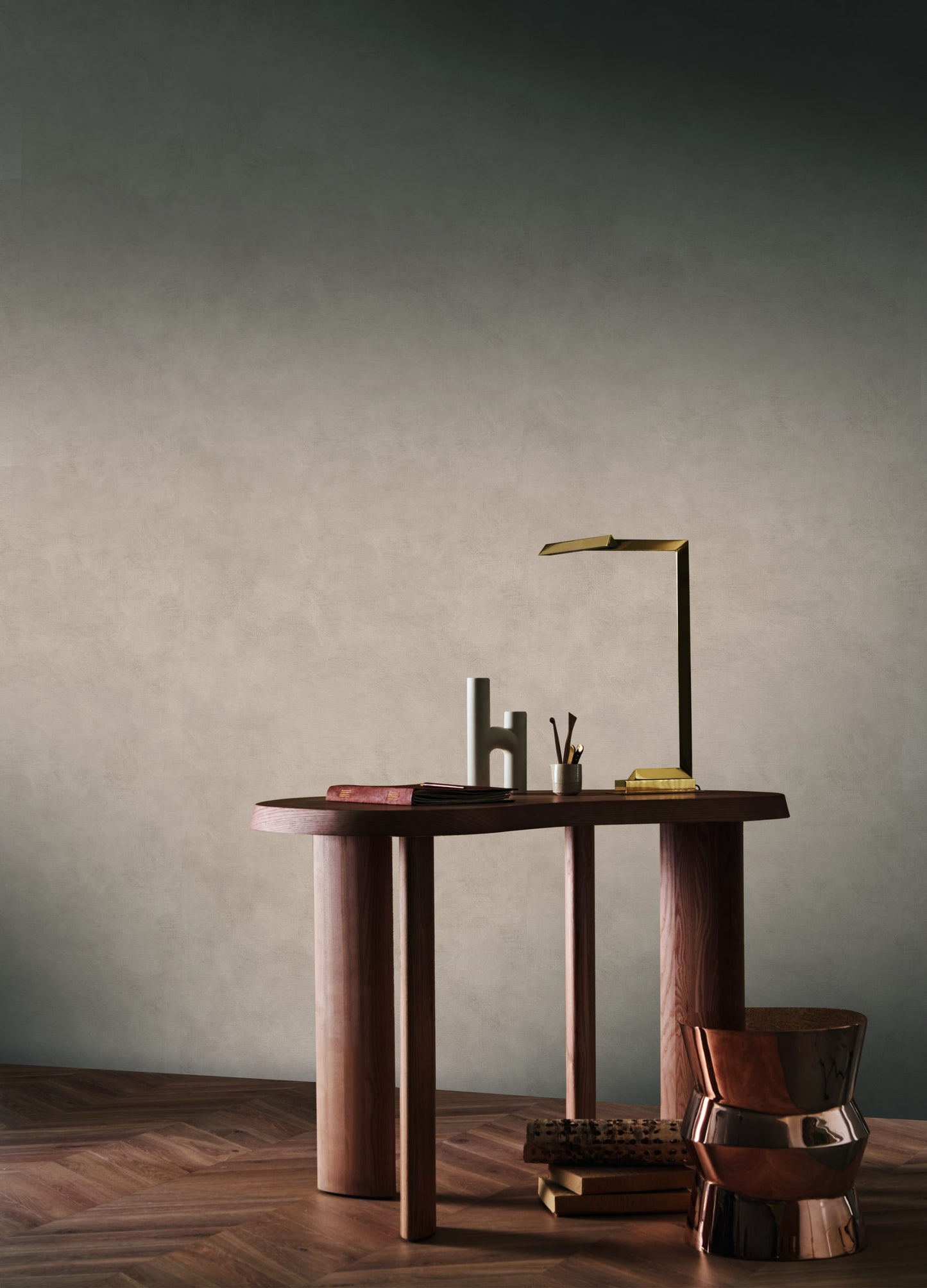 Casamance behang L'Atelier ARGILE effen behang in de kleur grijs met een hout bruine tafel en gouden lamp en bronze vaas