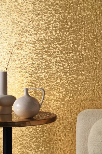 Casamance behang Métal pyrite patroon in goud met brons bijzettafel en een creme stoel 